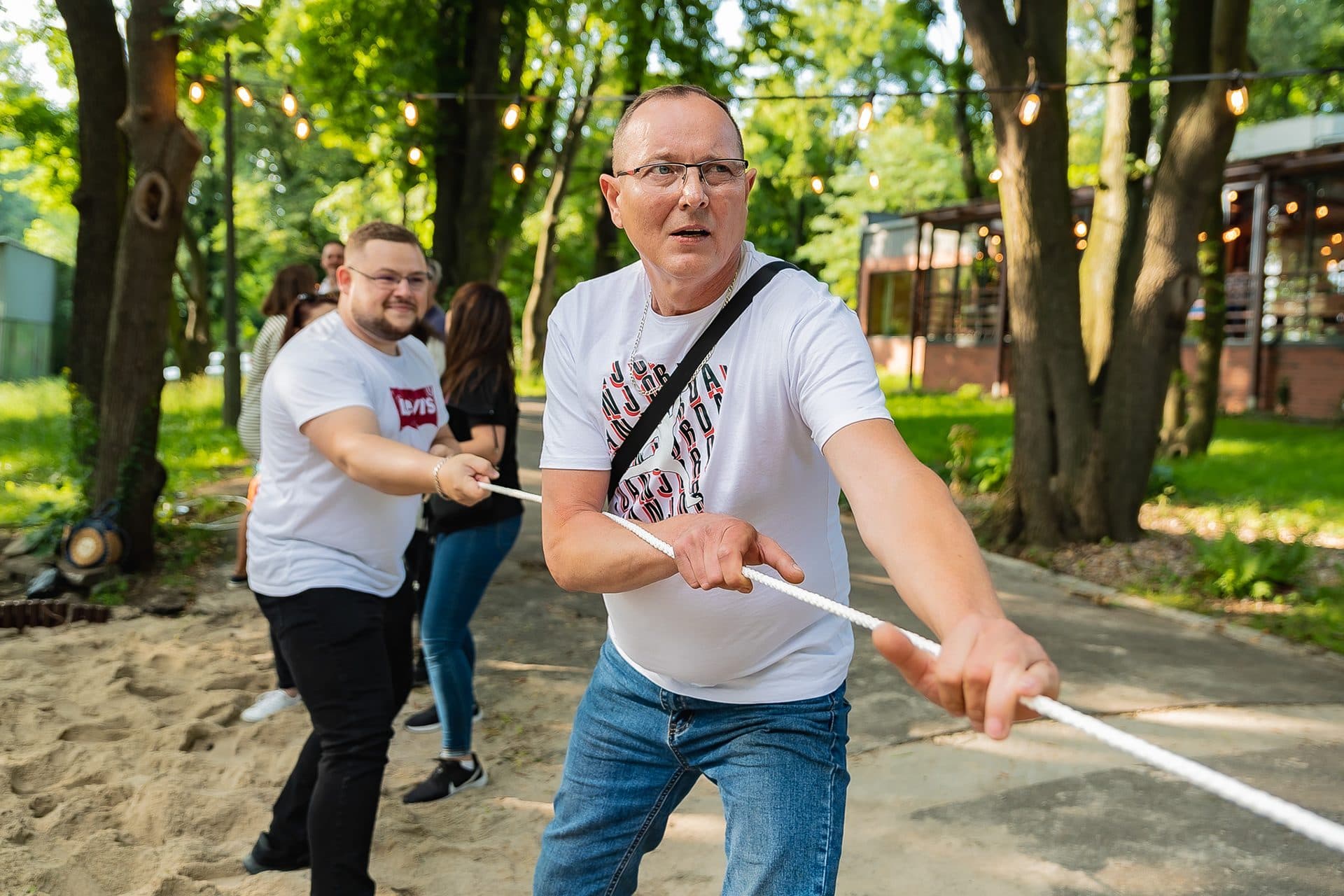 Przeciąganie liny na pikniku firmowym, uczestnicy w plenerze