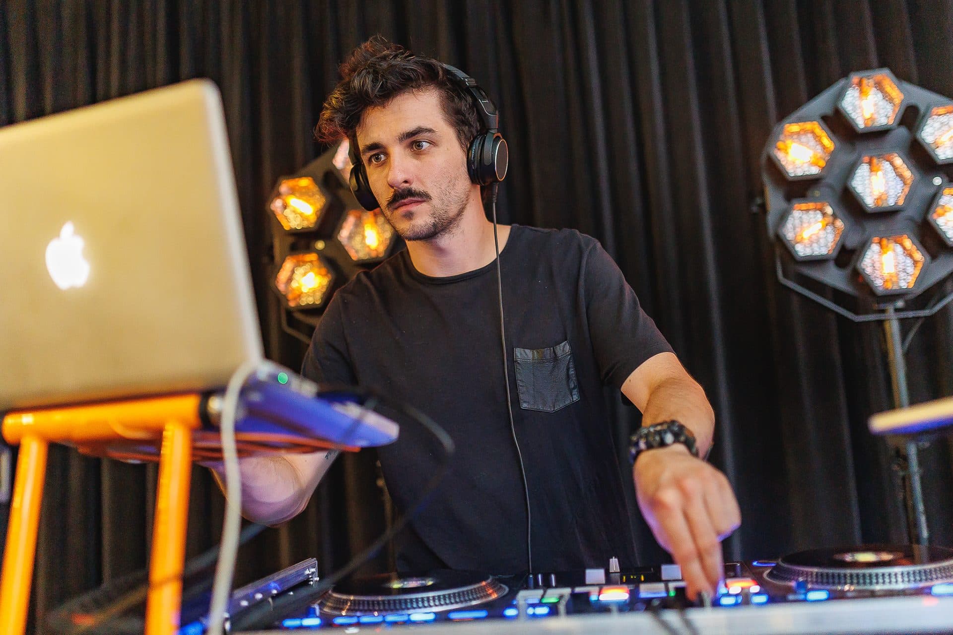 DJ przy konsolecie na imprezie firmowej, lampy sceniczne w tle