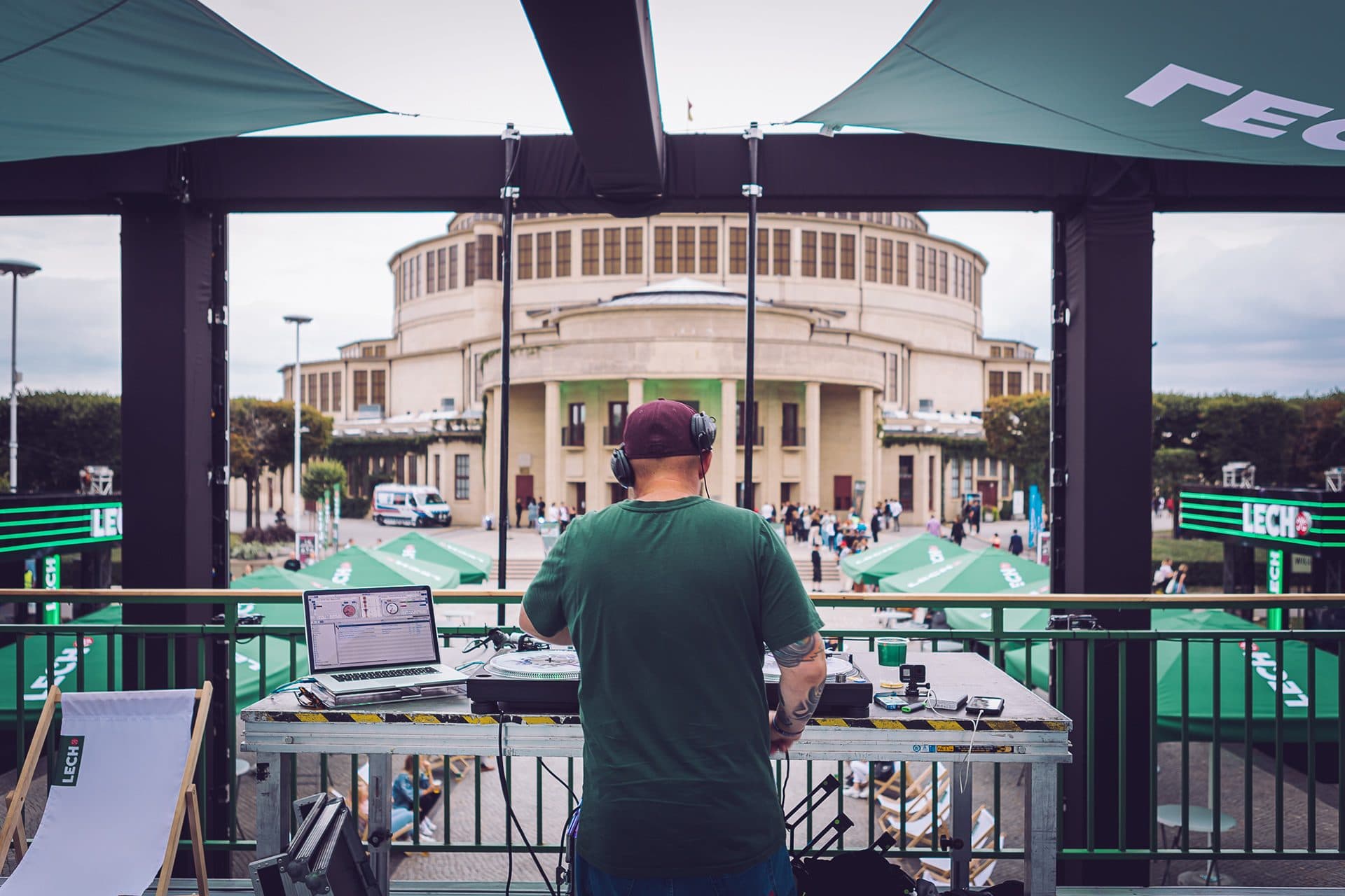 DJ na scenie plenerowej, w tle strefa gastronomiczna imprezy miejskiej