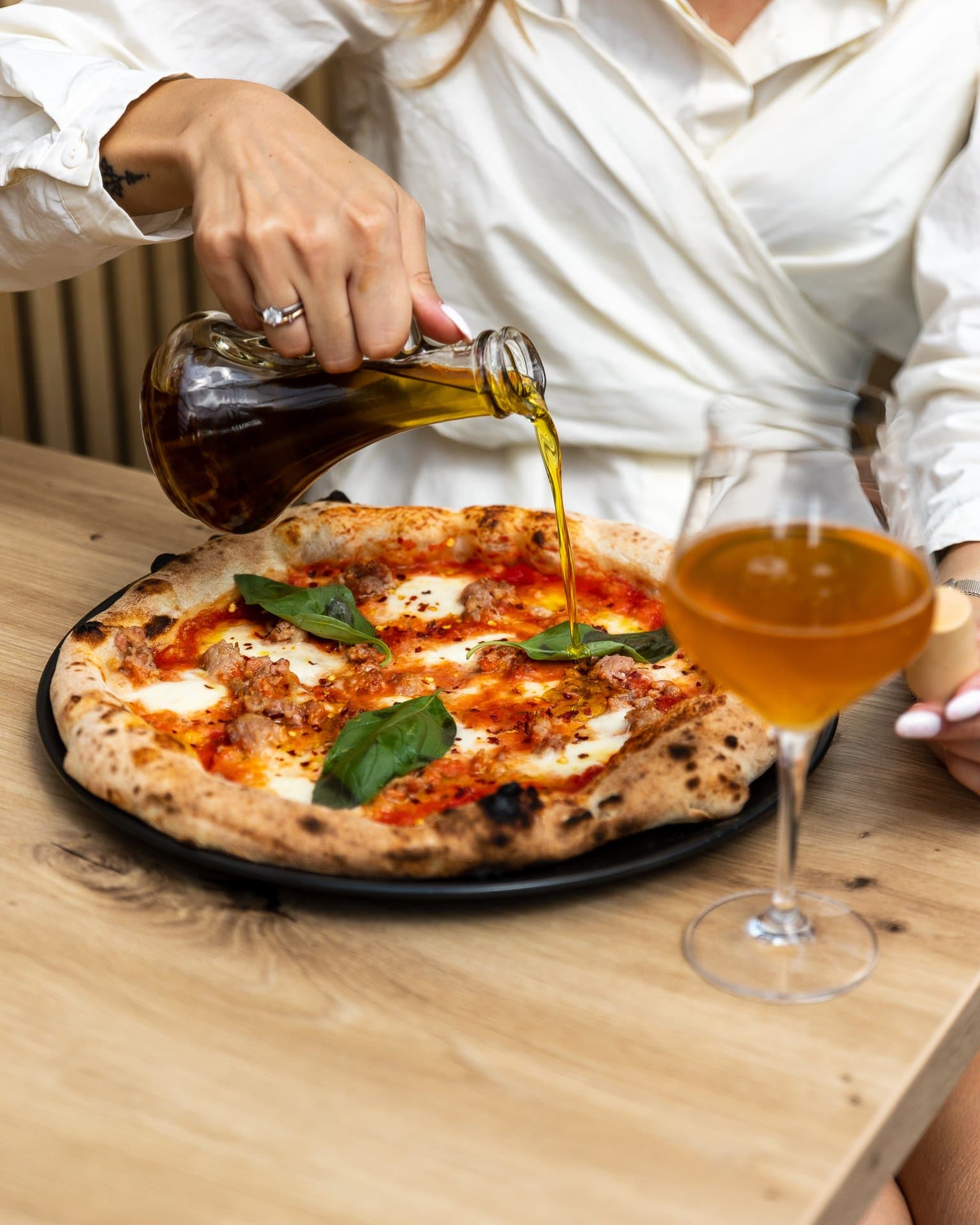 Oliwa polewana na pizzę neapolitańską, obok kieliszek wina, zdjęcie w lokalu