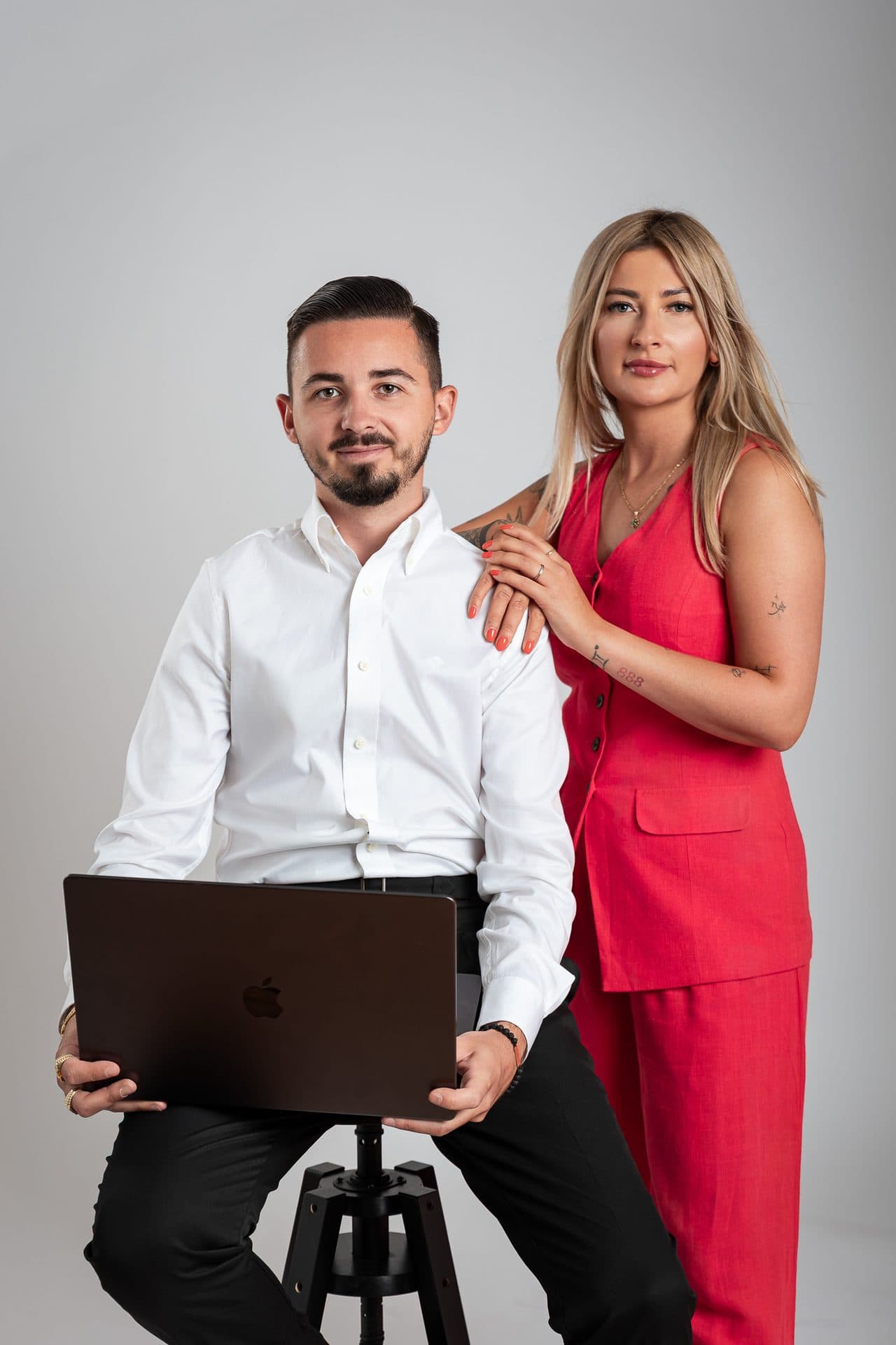Portret dwóch osób z jednej firmy, mężczyzna z laptopem i kobieta w czerwonym komplecie