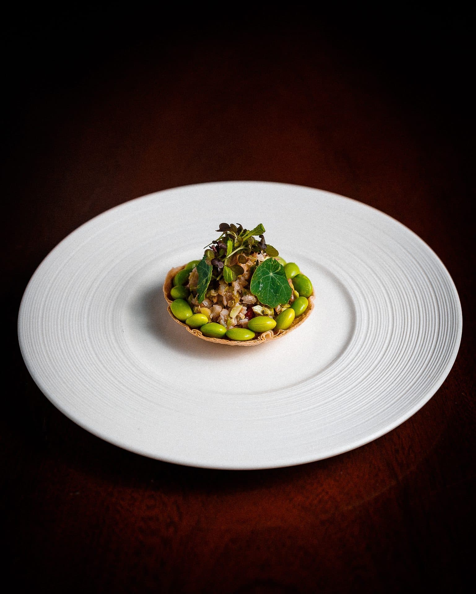 Tartaletka z zielonymi warzywami na białym talerzu, ciemne tło, fotografia kulinarna