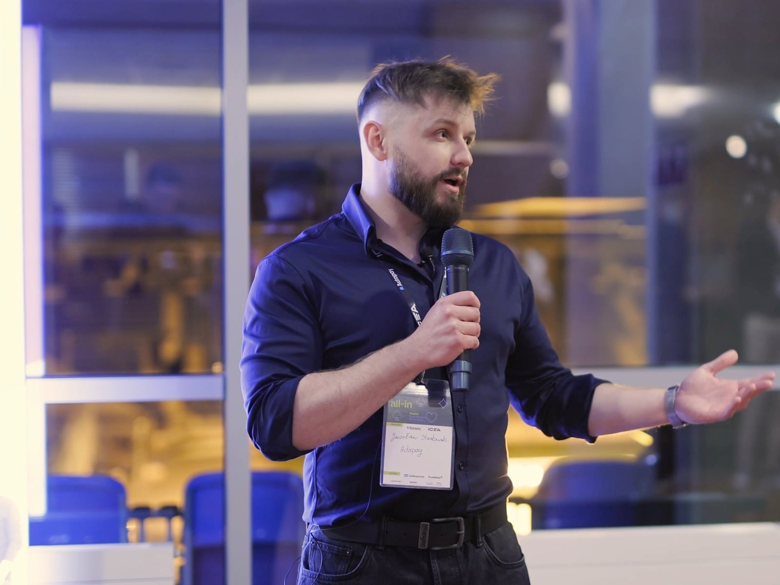Prelegent z mikrofonem podczas wystąpienia na E-commerce All In, identyfikator konferencyjny na smyczy