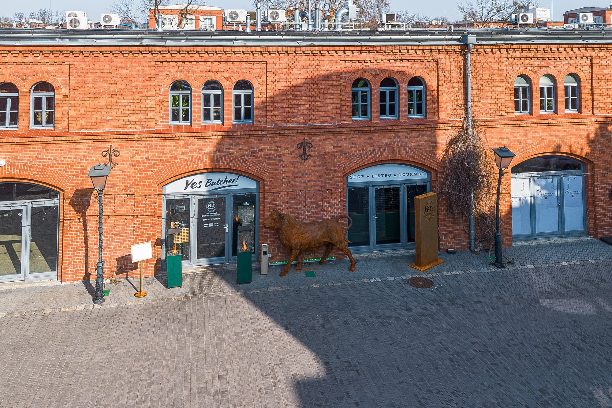 Budynek Yes Butcher! w Starych Koszarach z drona, ceglana fasada i rzeźba byka przed wejściem, Poznań