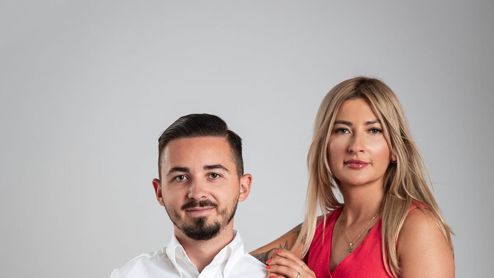 Studyjny portret dwojga osób na szarym tle, mężczyzna w białej koszuli i kobieta w czerwonej sukience